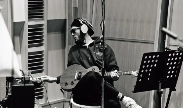 レコーディングスタジオでギターを弾く長瀬智也のモノクロ写真・音楽活動と年収イメージ