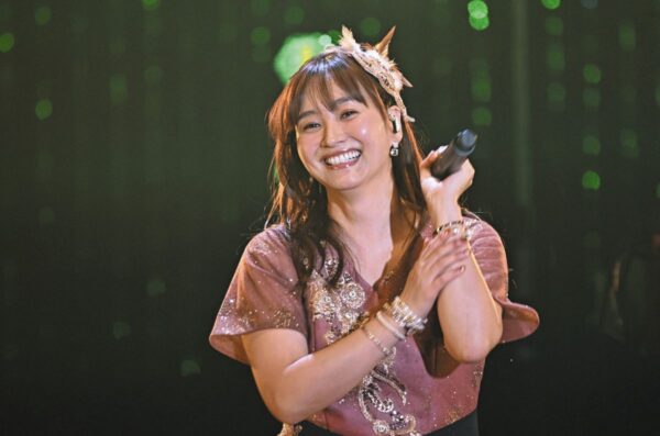 ステージ上でマイクを手に笑顔で歌う藤本美貴のライブ写真。きらびやかな衣装で観客にパフォーマンスする姿が印象的な、歌手活動と年収特集のアイキャッチに使える画像