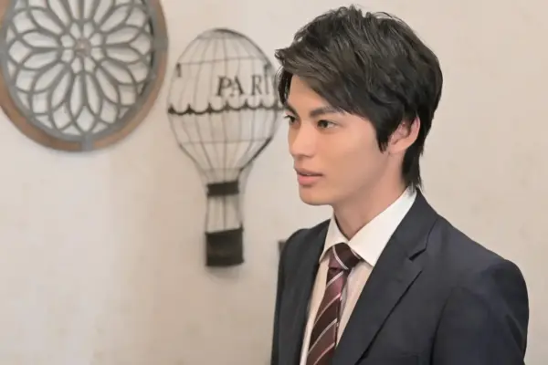 スーツ姿の若い男性俳優が室内で横向きに立ち真剣な表情で話しているドラマのビジネスシーン風ポートレート写真