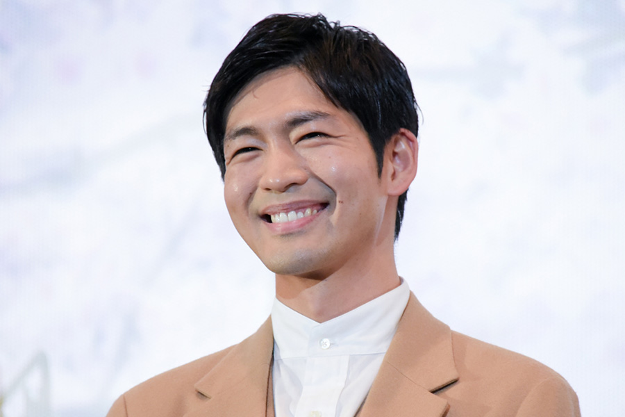 ベージュのジャケットを着た男性が満面の笑みを浮かべているアップ写真。柔らかな雰囲気のポートレートで、俳優の人気や人柄を伝える年収・経歴解説ブログのアイキャッチ画像に最適。