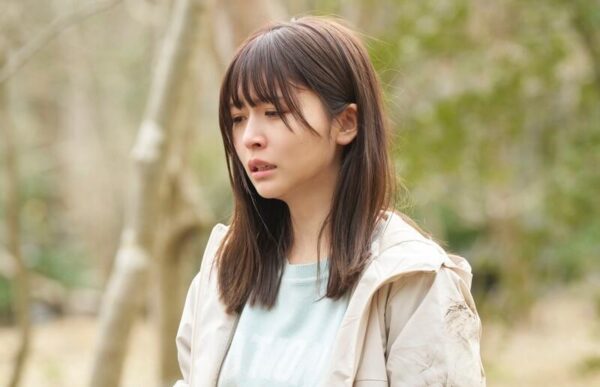 森の中で涙ぐむ若い女性のドラマシーンカット 感情的な演技が印象的な場面写真