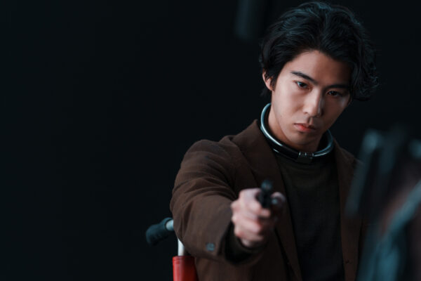 人気男性俳優のアクション場面写真｜スーツ姿で小道具を構える今年の出演作スチール