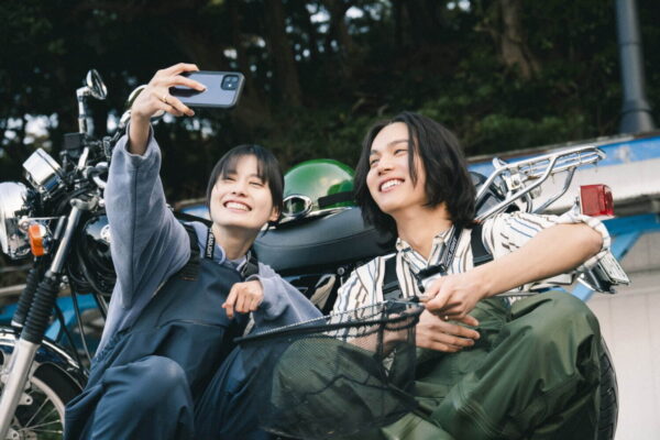バイクの前で自撮りする男女2人、釣り道具を手に笑顔のシーン（ファッション・ライフスタイル特集）