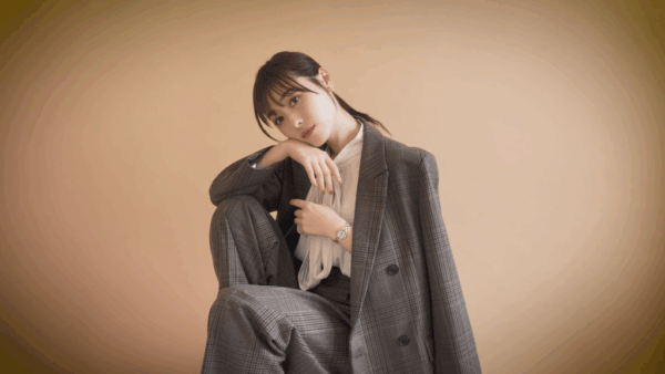 グレースーツ姿で椅子に腰掛けポーズをとる福原遥のスタジオ写真（クールなビジネス風アイキャッチ）