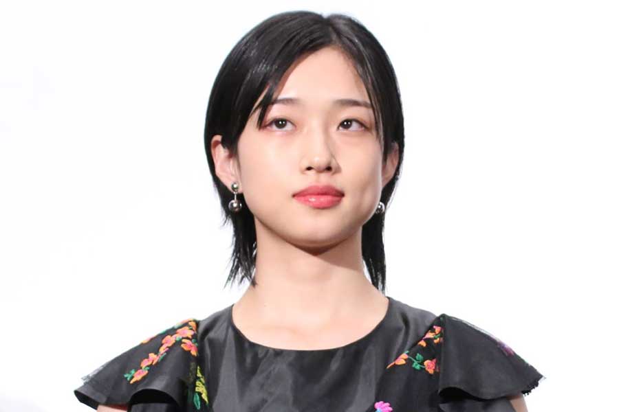 白背景の前で黒い衣装を着た若い女性のバストアップポートレート写真