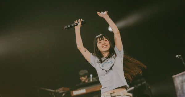 ライブステージで両手を挙げて笑顔を見せるあいみょんの写真（ツアー収入やライブ活動の勢いをイメージさせる年収記事用イメージカット）