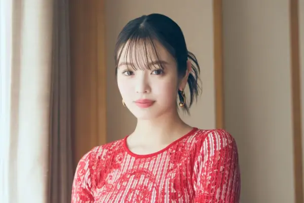 赤い柄ワンピースを着た横田真悠が室内の窓辺で柔らかく微笑み、年収やキャリアについて語るインタビュー記事用のポートレート写真