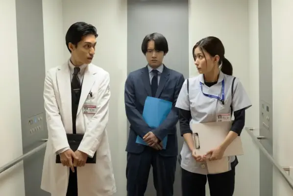 ドラマのエレベーター内のシーン。スーツ姿の男性と医師・看護師役の芳根京子が緊張感ある表情で対峙する場面