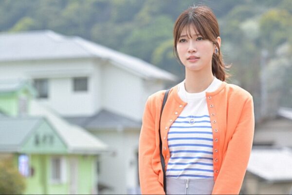 オレンジのカーディガンとボーダーTシャツ姿で街中に立つ生見愛瑠のドラマ出演シーン