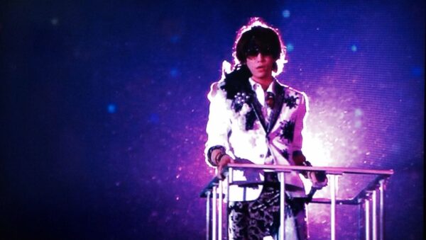 白い衣装の男性アイドルが紫のライトを浴びてステージに立つソロライブの場面