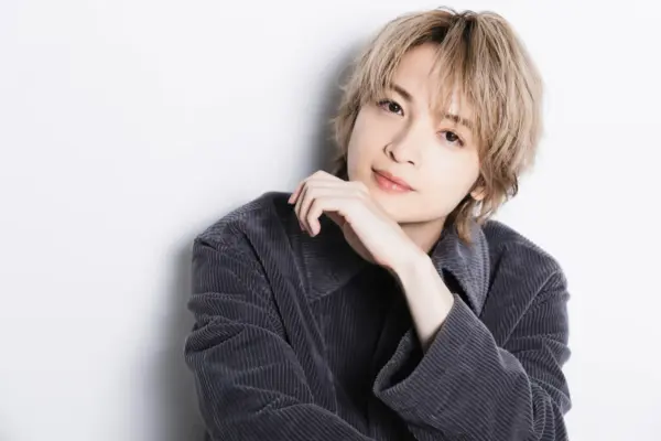 玉森裕太の経歴や年収推移を解説する記事用イメージとして、金髪の若い男性がグレーのジャケットを着て柔らかく微笑む上半身ポートレート写真