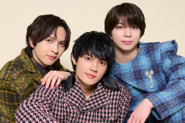 3人の男性アーティストがカメラ目線で寄り添うスリーショット写真。チェック柄など個性的な衣装のビジュアル